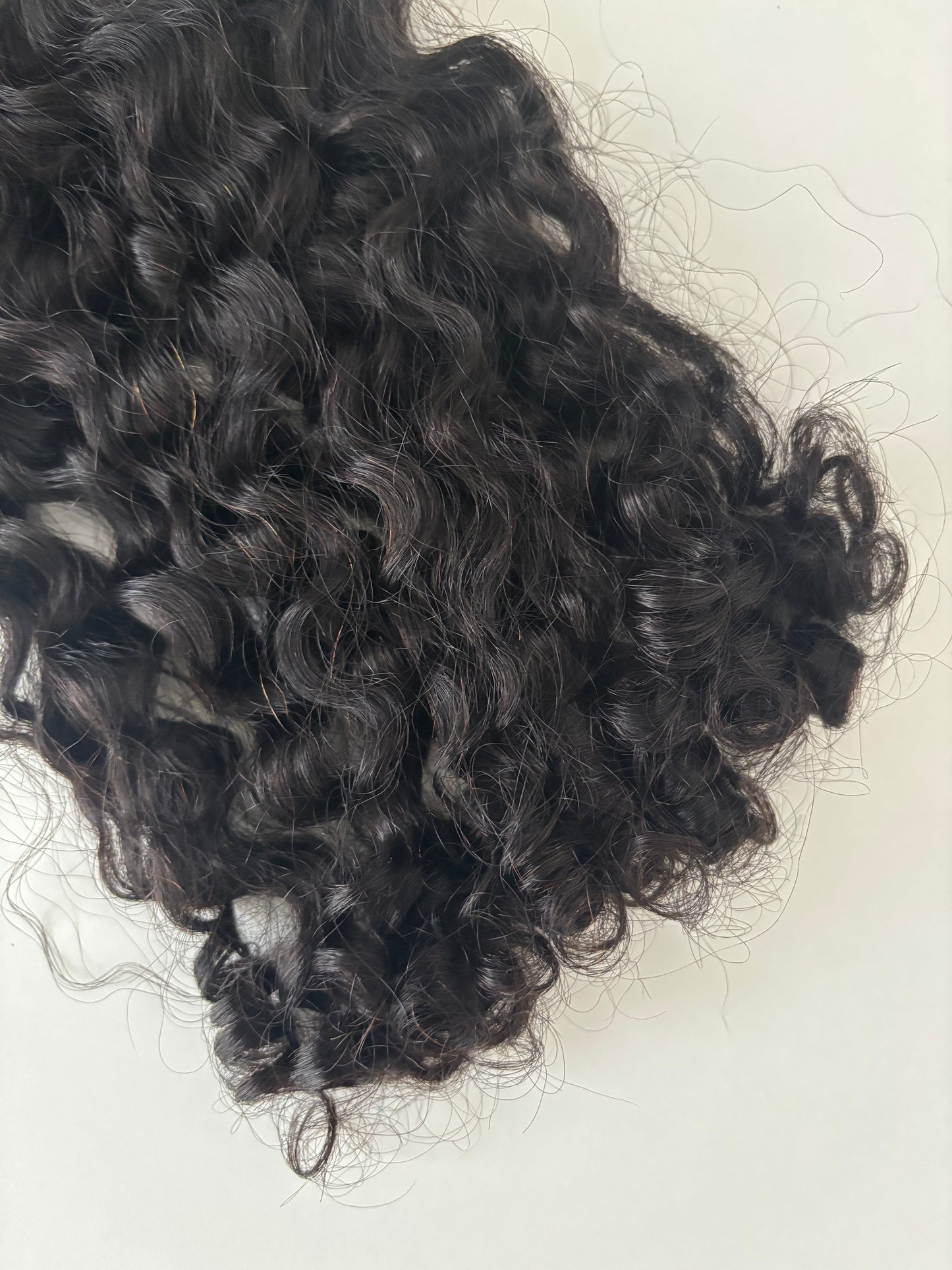 Curly black hair extensions on a cream background