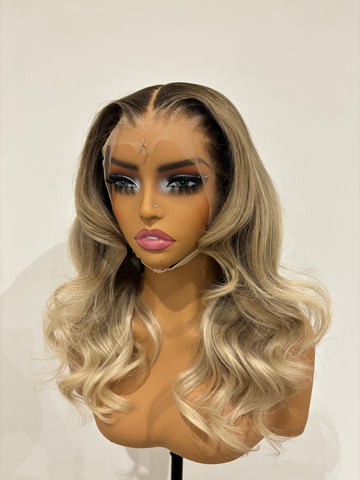 Blonde wig on a mannequin head against a plain background