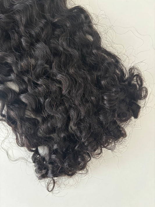 Curly black hair extensions on a cream background