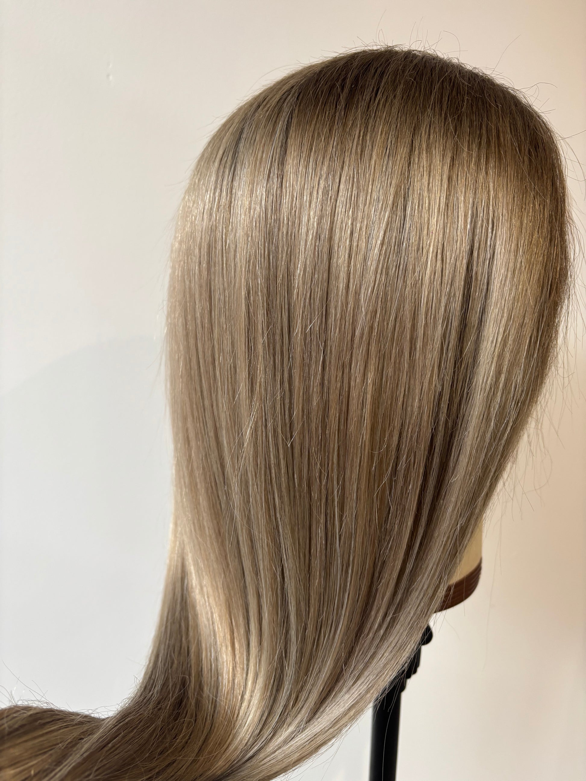 Close-up of straight, blonde hair on a plain background